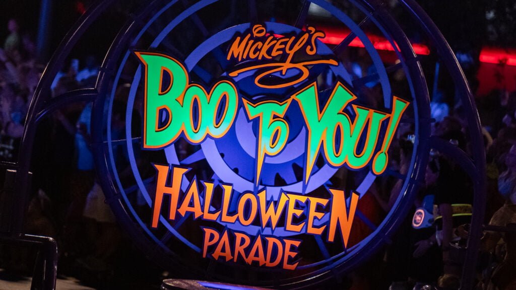 Signage for "Mickey's Boo to You! Halloween Parade" with colorful text and glowing effects.