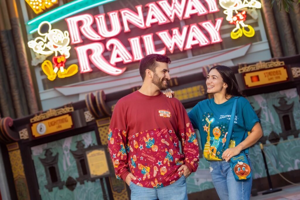 Two people smiling at each other stand in front of a neon sign that says "Runaway Railway," with a Mickey Mouse graphic.