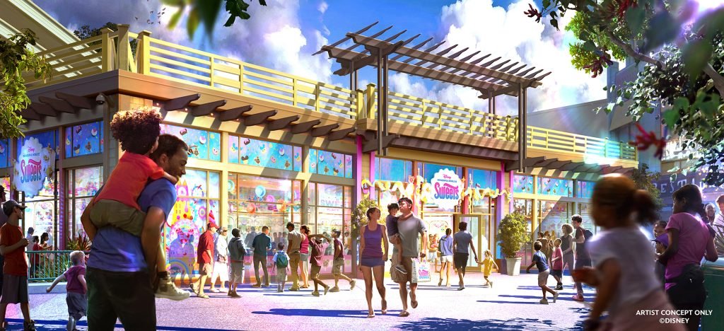 People walking outside a colorful candy store with large glass windows and vibrant decorations.