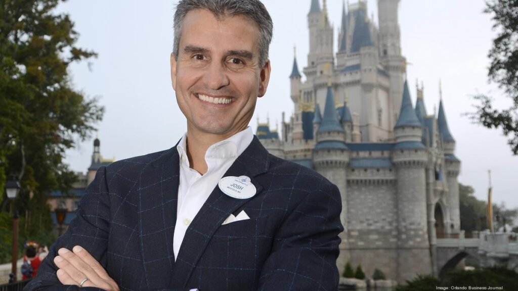 Portrait of Josh D'Amaro, Disney Experiences Chairman, in front of a theme park castle.