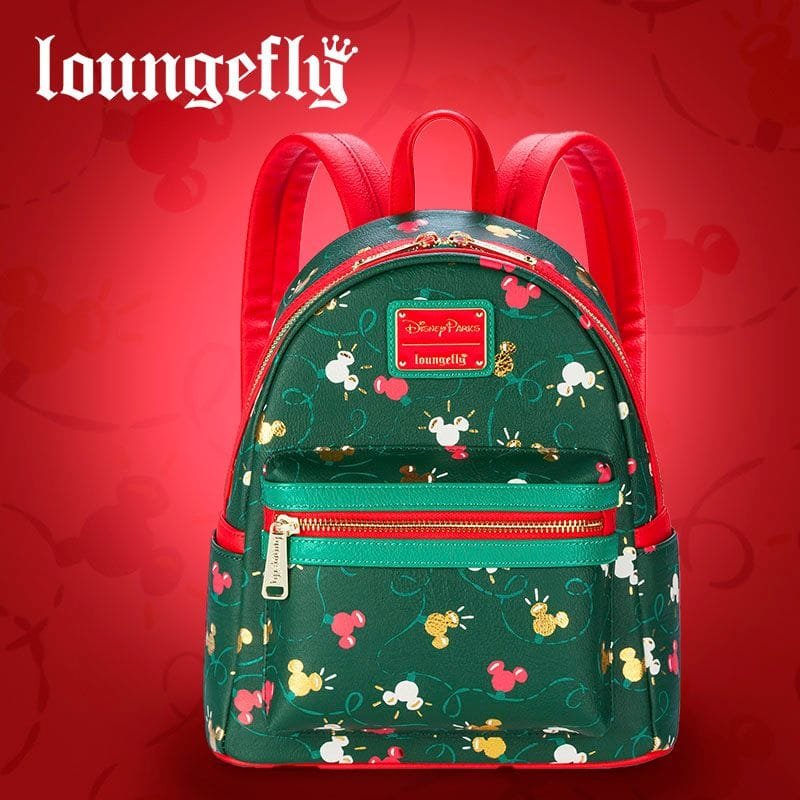 A small, green backpack with a playful design featuring colorful Mickey Mouse silhouettes, red accents, and a front zip pocket, set against a red background.