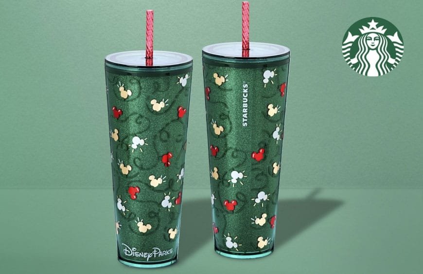 Two tall, glittery green Starbucks tumblers with a design featuring colorful Mickey Mouse heads in red, white, and gold, along with decorative swirls. Each tumbler has a light blue rim and a pink straw. A Starbucks logo is visible in the top right corner.