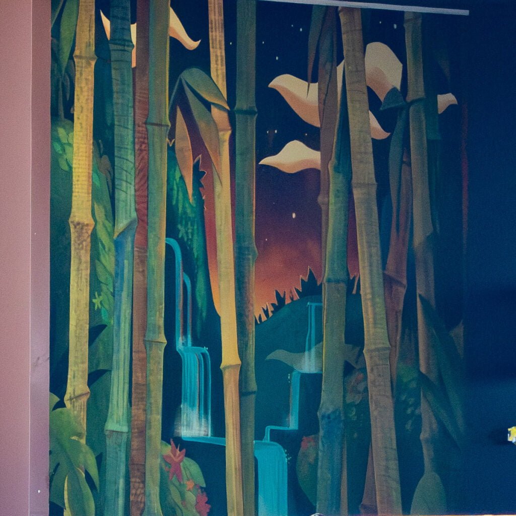 A colorful mural depicting tall bamboo stalks, lush green foliage, and cascading waterfalls, set against a twilight sky with soft clouds and stars.