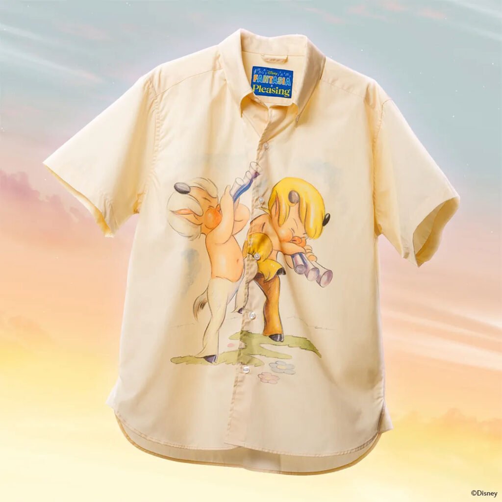 A light yellow short-sleeved shirt featuring a whimsical illustration of two animated animals playing flutes, set against a soft, pastel-colored background.