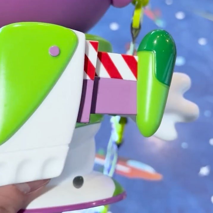 A close-up of a Buzz Lightyear toy with an extended wing on a blue background.
