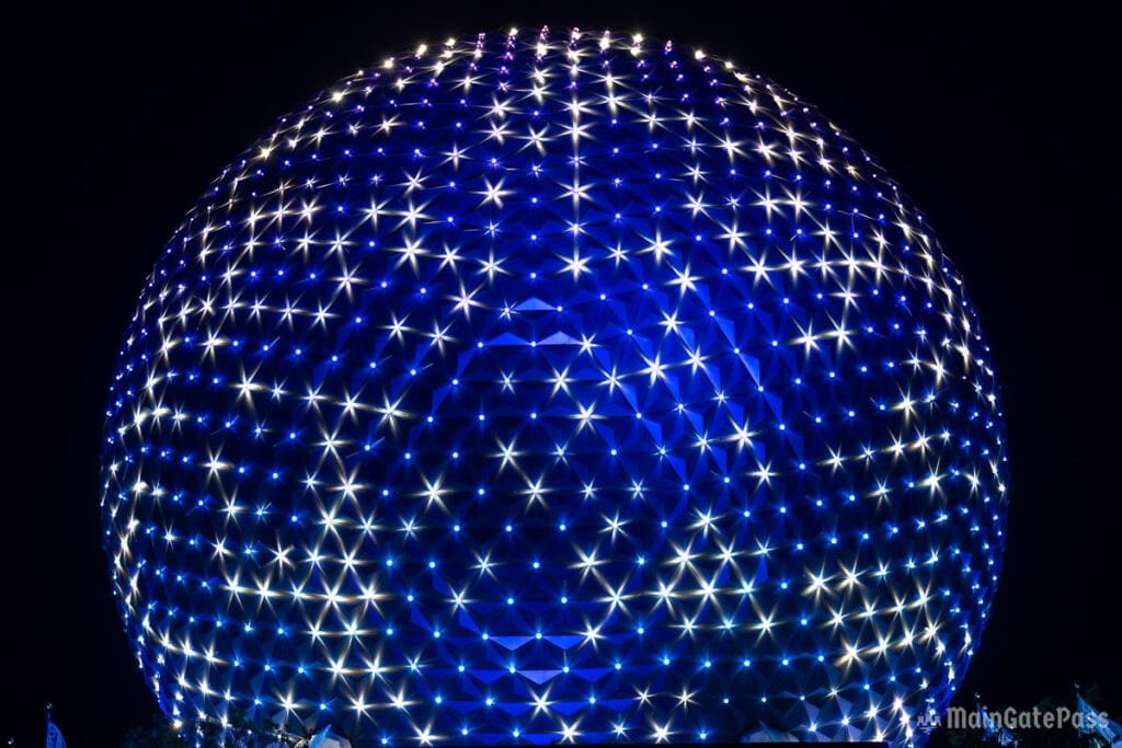 A large dome structure illuminated with blue and white lights, creating a star-like pattern against a dark night sky.