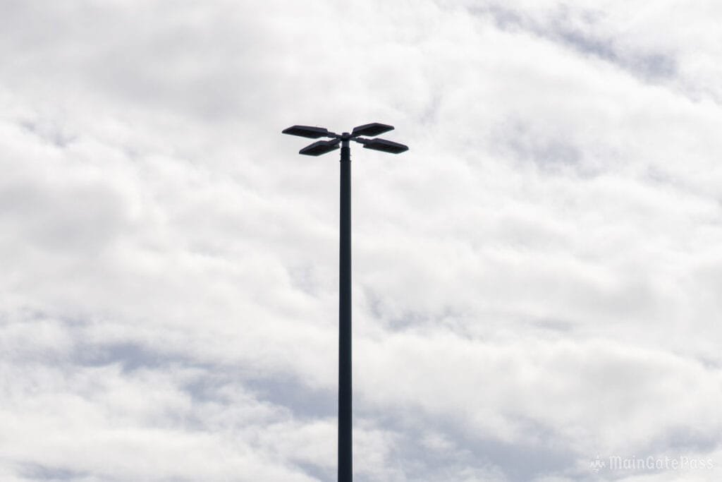 A tall streetlight with four angled light fixtures silhouetted against a cloudy sky.