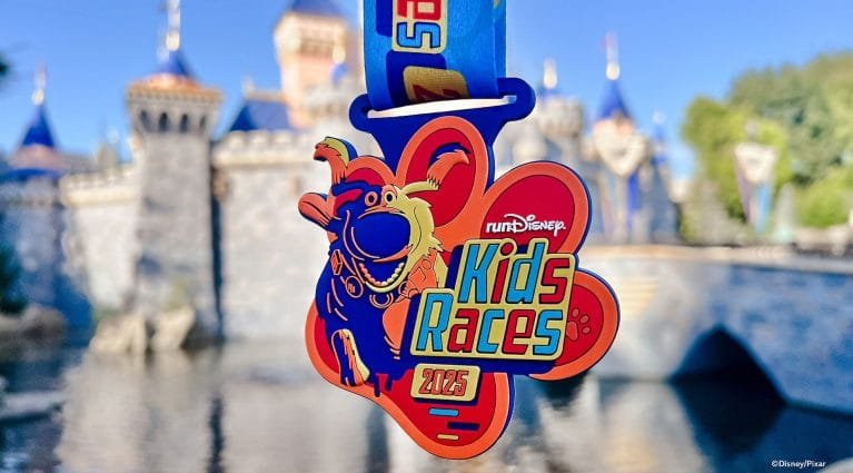 A colorful medal for the "Kids Races 2025" event featuring a cartoon character, hanging on a blue ribbon, with a castle backdrop.